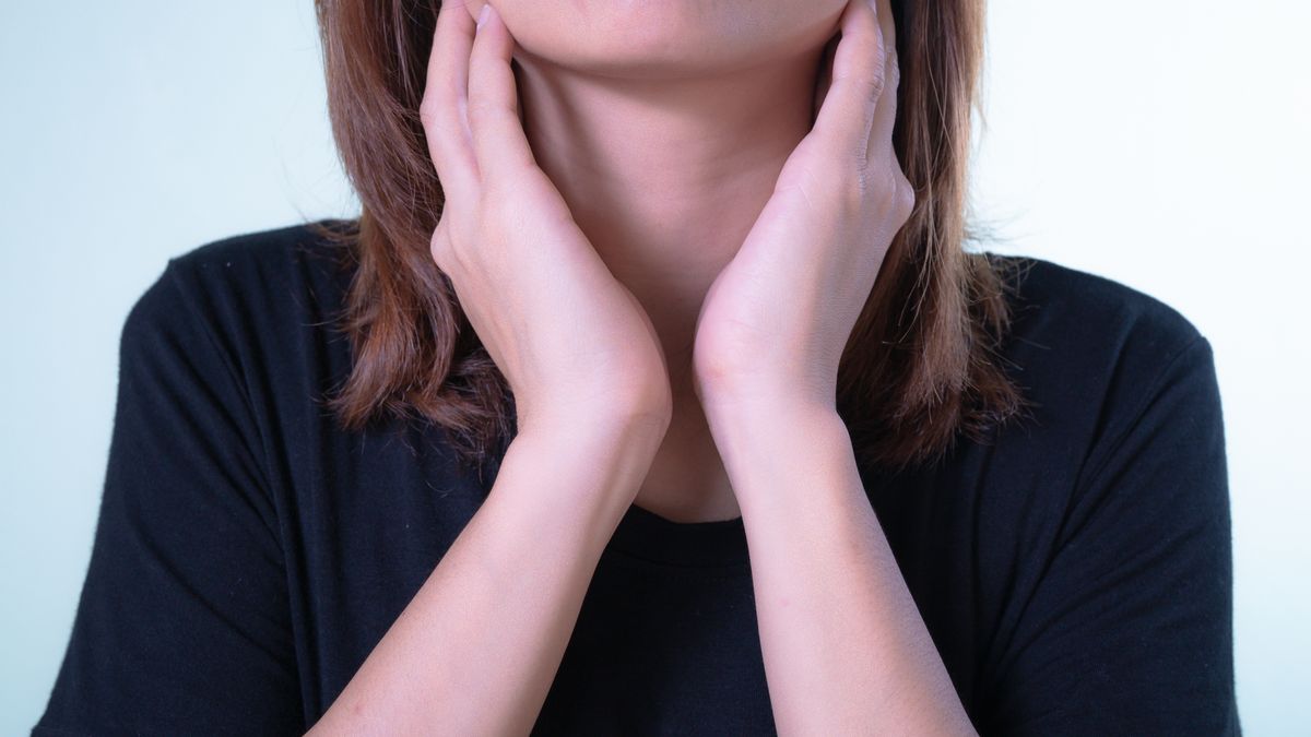 Woman touching her neck near the thyroid, considering an at-home thyroid and hormone test