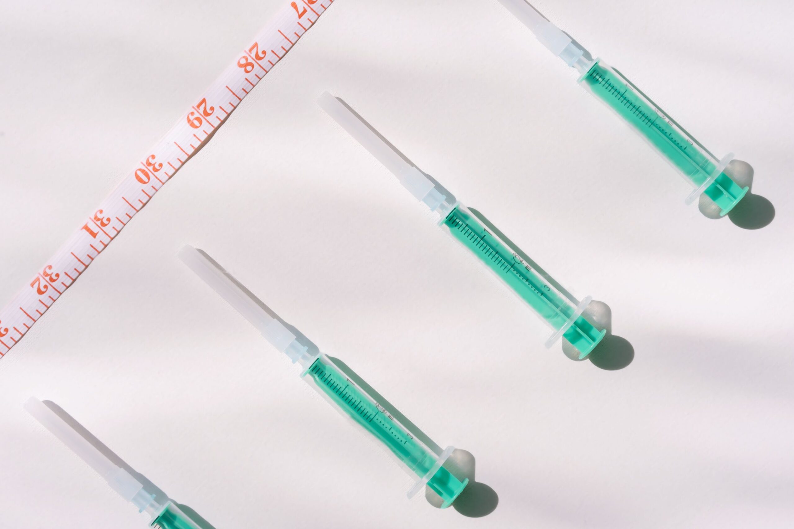 GLP-1 weight-loss medication syringes and a measuring tape, representing online telehealth treatment