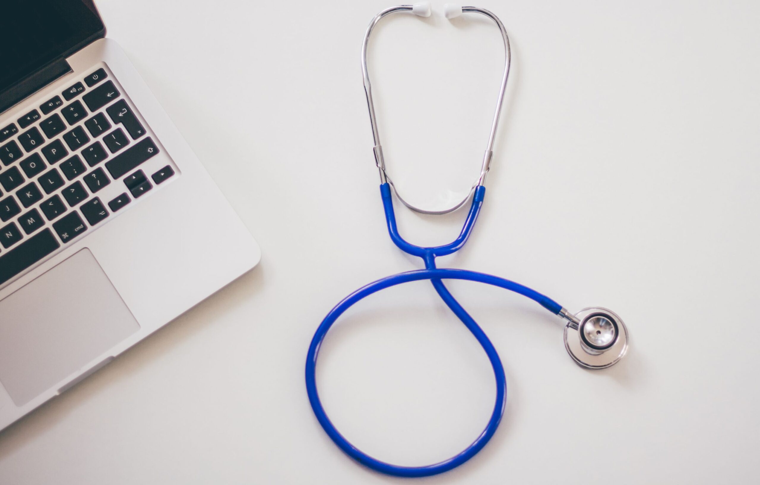 A stethoscope beside a laptop on a clean white desk, representing digital full-body blood test dashboards from Superpower and Function Health